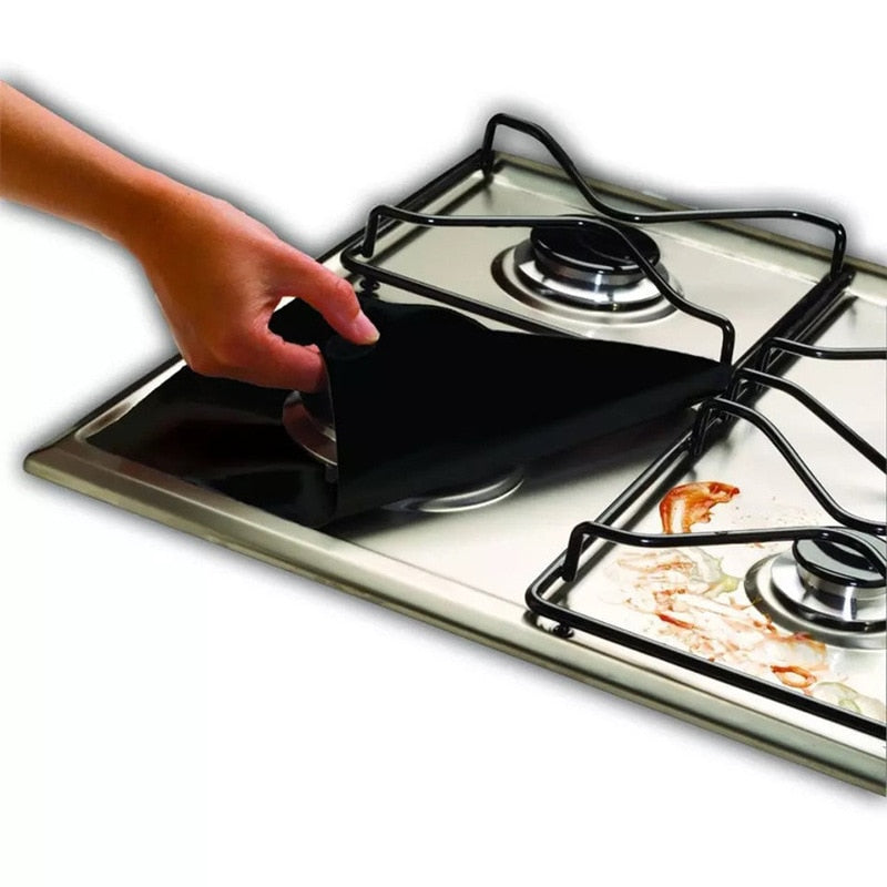 Hand peeling black silicone stove burner cover off stainless steel gas stove with food stains