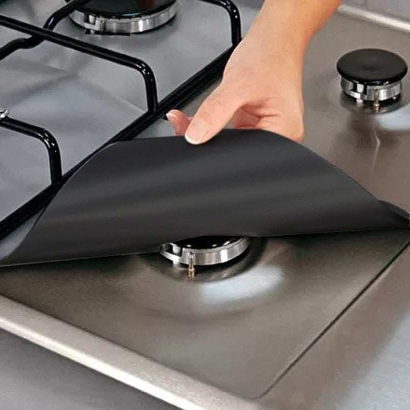 Hand placing black silicone stove burner cover on stainless steel gas cooktop for protection and easy cleaning